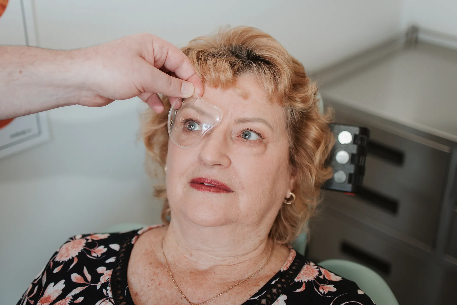 A clear protective eye shield being fitted over a patient's eye after cataract surgery